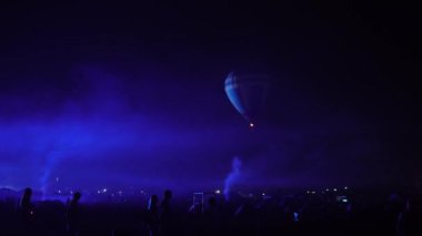 Gece kızdırma sıcak hava balon topluluk Festivali. Pilot yavaş hareketli sıcak hava balonları almaya hazır olun. Isıtır renkli kumaş içinde ateş. Akşam gece karanlık kırsal topluluk.
