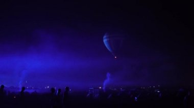 Gece kızdırma sıcak hava balon topluluk Festivali. Pilot yavaş hareketli sıcak hava balonları almaya hazır olun. Isıtır renkli kumaş içinde ateş. Akşam gece karanlık kırsal topluluk.