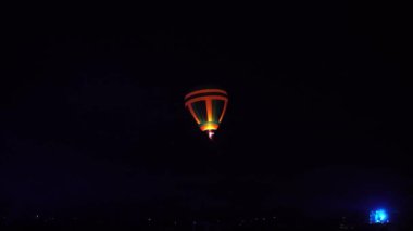 Gece kızdırma sıcak hava balon topluluk Festivali. Pilot yavaş hareketli sıcak hava balonları almaya hazır olun. Isıtır renkli kumaş içinde ateş. Akşam gece karanlık kırsal topluluk.