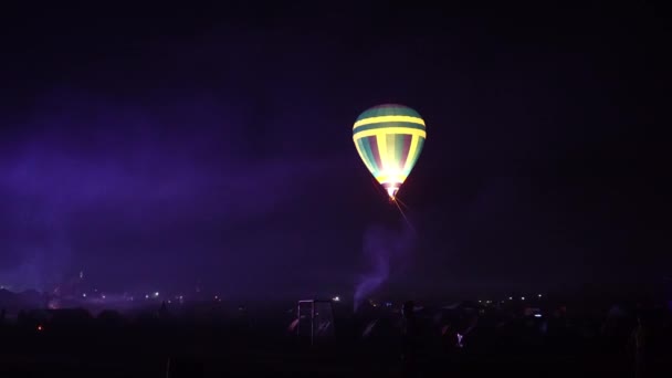 Night glow hot air balloon community festival. Pilot prepare to take slow moving hot air balloons. Fire heats inside of colorful fabric. Evening night dark rural community. — Stock Video