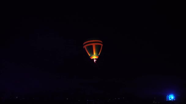 夜辉光热气球社区节。飞行员准备采取慢速移动热气球。火在五颜六色的布料里面加热。夜晚黑暗的乡村社区. — 图库视频影像