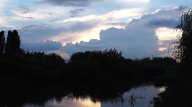 Havadan görünümü: Yeşil ahşap ve güzel nehir üzerine uçuş. Pastel bulutlu gökyüzü günbatımı soft light. Magestic manzara. 4 k çözünürlük.