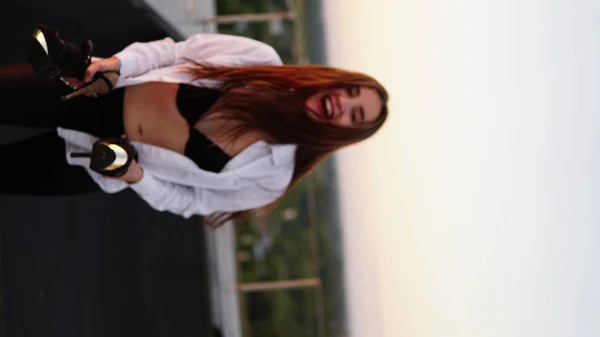 Young girl in sports uniform sits on the edge of the roof during sunset. — Stock Photo, Image