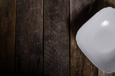 Kopya alanı ile ahşap arka plan üzerinde boş beyaz çanak ve beyaz masa örtüsü üst görünümü.