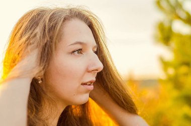 Haşhaş tarlasında poz veren gösterişli kırmızı elbiseli güzel bir kız. Gün batımında haşhaş tarlası. Sanat işleme. Günbatımı