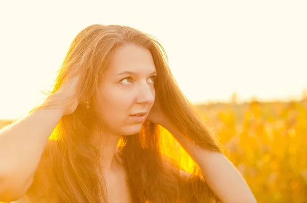 Schöne Mädchen in einem noblen roten Kleid posiert auf einem Mohnfeld. Mohnfeld bei Sonnenuntergang. Kunstverarbeitung. Sonnenuntergang — Stockfoto