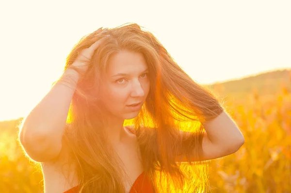 Krásná dívka v nóbl červených šatech na makové poli. Makavé pole při západu slunce. Umělecké zpracování. Západ slunce — Stock fotografie