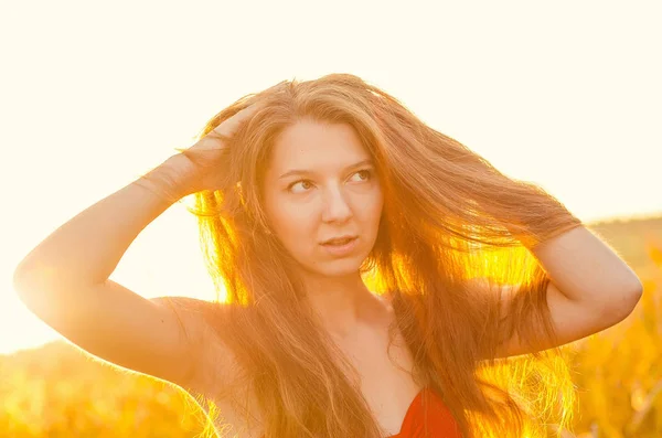 Menina bonita em um vestido vermelho elegante posando em um campo de papoula. Campo Poppy ao pôr-do-sol. Processamento de arte. Pôr do sol — Fotografia de Stock