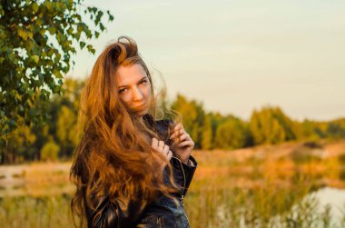 Haşhaş tarlasında poz veren gösterişli kırmızı elbiseli güzel bir kız. Gün batımında haşhaş tarlası. Sanat işleme. Günbatımı