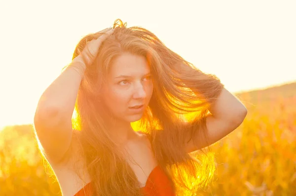 Krásná dívka v nóbl červených šatech na makové poli. Makavé pole při západu slunce. Umělecké zpracování. Západ slunce — Stock fotografie