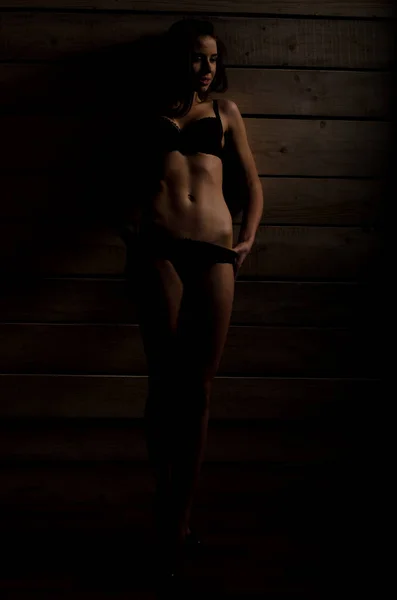 Bella ragazza sexy in costume da bagno nero su uno sfondo di tavole lucide — Foto Stock
