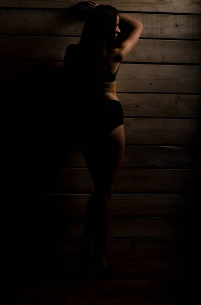 Vacker sexig tjej i en svart baddräkt på en bakgrund av polerad styrelser — Stockfoto