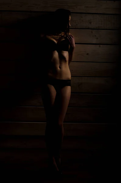 Красивая сексуальная девушка в черном купальнике на фоне полированных досок — стоковое фото