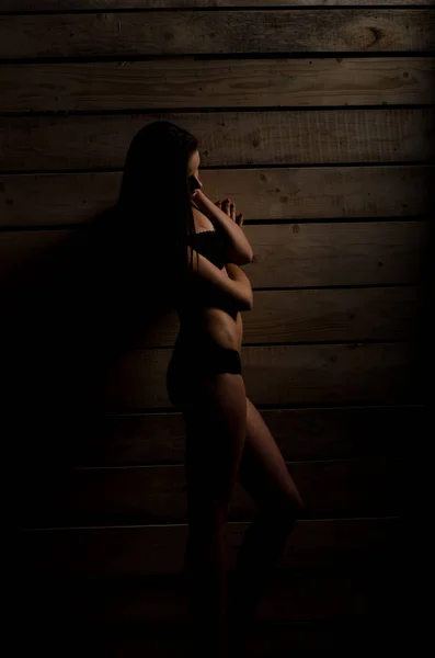 Vacker sexig tjej i en svart baddräkt på en bakgrund av polerad styrelser — Stockfoto