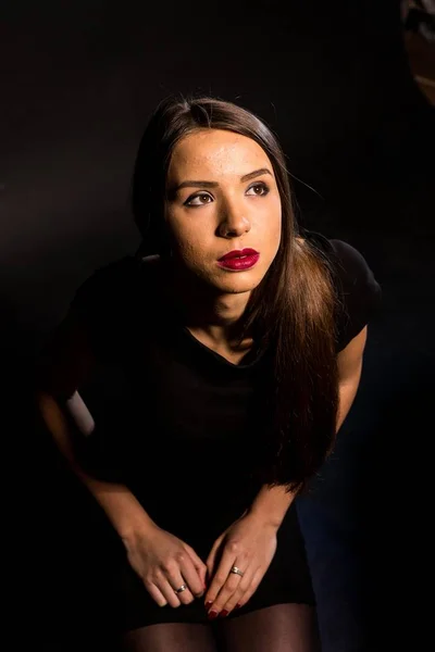 Retrato de uma bela jovem mulher em um vestido preto com uma maquiagem legal e boa pele. Estúdio, fundo preto . — Fotografia de Stock