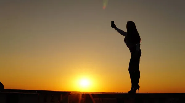 Junges Mädchen in Sportuniform sitzt bei Sonnenuntergang auf dem Dachrand. — Stockfoto