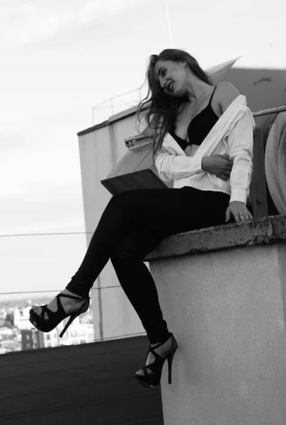 Молодая сексуальная женщина позирует на крыше, одета в кожаную куртку, шикарно — стоковое фото