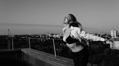 Genç seksi kadın çatıda poz, leater ceket giyen, çiçek şapka yansıtılan güneş gözlüğü ve parlak makyaj, Vintage kamera tutarak, Lifestyle portre