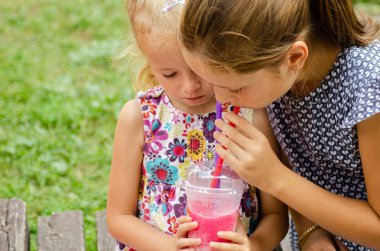 parkta kokteyl veya limonata içen kız kardeşler 