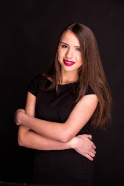 güzel makyaj ve iyi bir cilt ile siyah elbiseli güzel bir genç kadının portresi. Stüdyo, siyah arka plan.