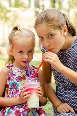 parkta kokteyl veya limonata içen kız kardeşler 