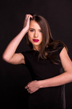 güzel makyaj ve iyi bir cilt ile siyah elbiseli güzel bir genç kadının portresi. Stüdyo, siyah arka plan.