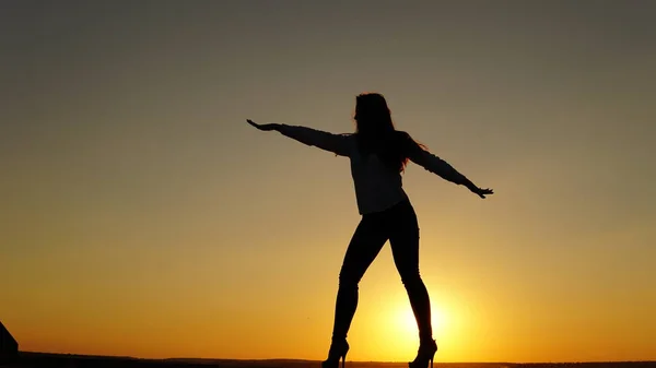 Young girl in sports uniform sits on the edge of the roof during sunset. — Stock Photo, Image