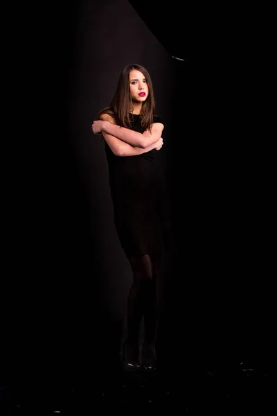 Retrato de uma bela jovem mulher em um vestido preto com uma maquiagem legal e boa pele. Estúdio, fundo preto . — Fotografia de Stock