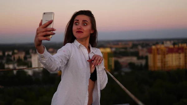 Utomhus porträtt av vacker flicka tar en selfie på taket. — Stockfoto