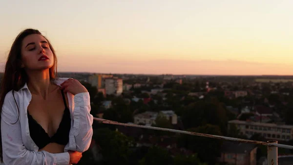 Junges Mädchen in Sportuniform sitzt bei Sonnenuntergang auf dem Dachrand. — Stockfoto