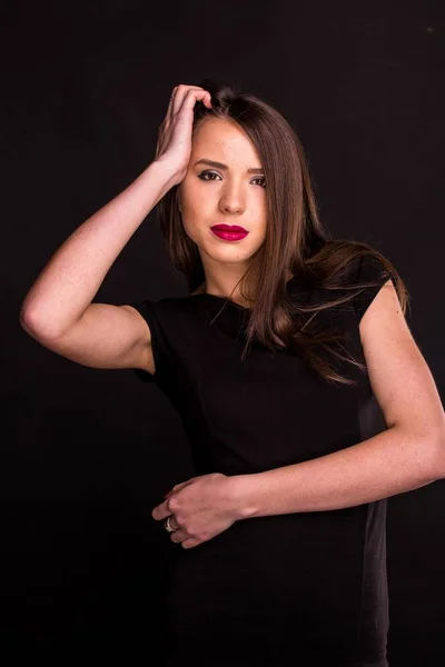 Retrato de uma bela jovem mulher em um vestido preto com uma maquiagem legal e boa pele. Estúdio, fundo preto . — Fotografia de Stock