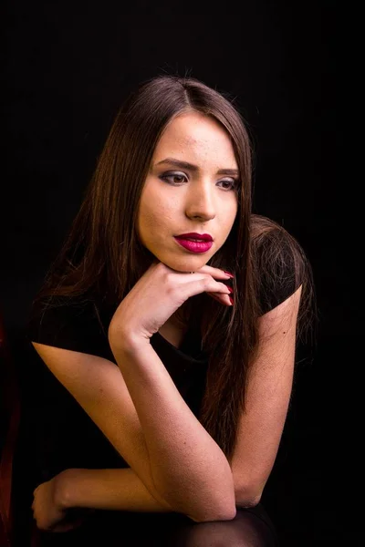 Portrait d'une belle jeune femme en robe noire avec un maquillage cool et une bonne peau. Studio, fond noir . — Photo