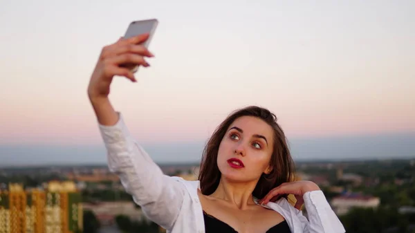 Plenerowej piękna dziewczyna biorąc selfie na dachu. — Zdjęcie stockowe
