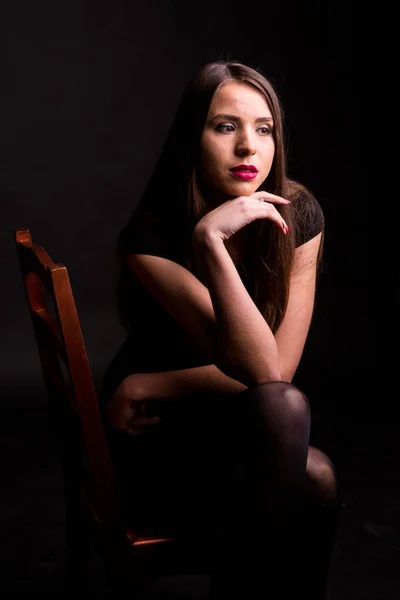 Retrato de uma bela jovem mulher em um vestido preto com uma maquiagem legal e boa pele. Estúdio, fundo preto . — Fotografia de Stock