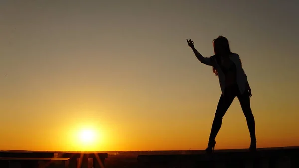 Junges Mädchen in Sportuniform sitzt bei Sonnenuntergang auf dem Dachrand. — Stockfoto