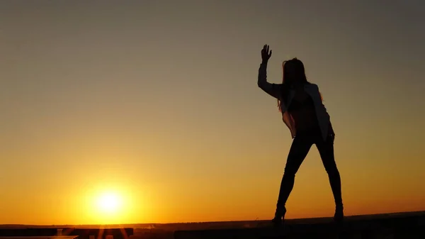 Giovane ragazza in uniforme sportiva si siede sul bordo del tetto durante il tramonto . — Foto Stock