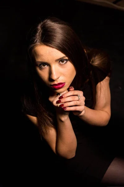 Porträtt av en vacker ung kvinna i en svart klänning med en cool makeup och bra hud. Studio, svart bakgrund. — Stockfoto