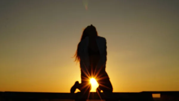 Chica joven en uniforme deportivo se sienta en el borde del techo durante el atardecer . — Foto de Stock