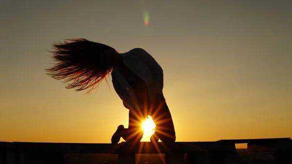 Junges Mädchen in Sportuniform sitzt bei Sonnenuntergang auf dem Dachrand. — Stockfoto