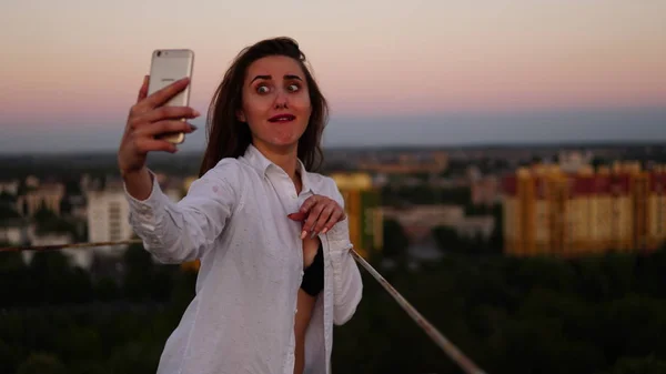 Retrato al aire libre de una hermosa chica tomando una selfie en el techo . — Foto de Stock