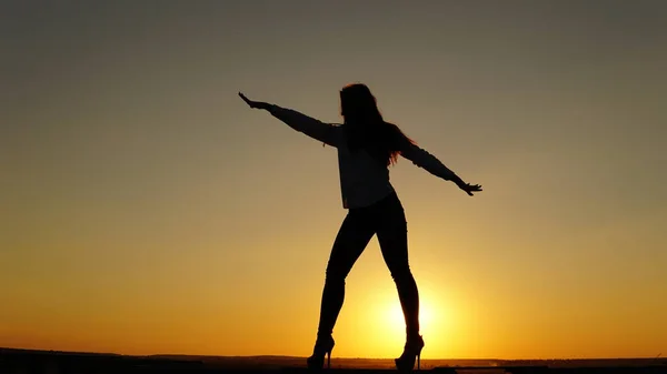 Jeune fille en uniforme de sport assis sur le bord du toit pendant le coucher du soleil . — Photo