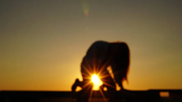 Young girl in sports uniform sits on the edge of the roof during sunset. — Stock Photo, Image