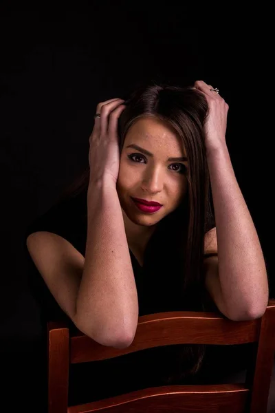 Retrato de uma bela jovem mulher em um vestido preto com uma maquiagem legal e boa pele. Estúdio, fundo preto . — Fotografia de Stock