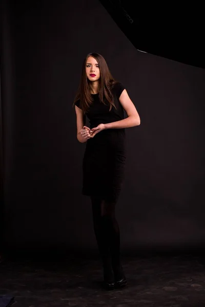 Retrato de uma bela jovem mulher em um vestido preto com uma maquiagem legal e boa pele. Estúdio, fundo preto . — Fotografia de Stock