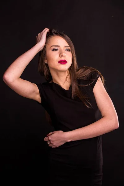 Retrato de uma bela jovem mulher em um vestido preto com uma maquiagem legal e boa pele. Estúdio, fundo preto . — Fotografia de Stock