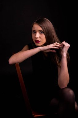 güzel makyaj ve iyi bir cilt ile siyah elbiseli güzel bir genç kadının portresi. Stüdyo, siyah arka plan.