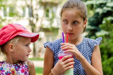 parkta kokteyl veya limonata içen kız kardeşler 