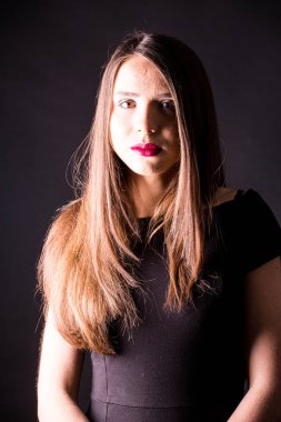 güzel makyaj ve iyi bir cilt ile siyah elbiseli güzel bir genç kadının portresi. Stüdyo, siyah arka plan.