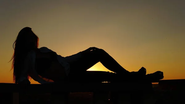 Jeune fille en uniforme de sport assis sur le bord du toit pendant le coucher du soleil . — Photo
