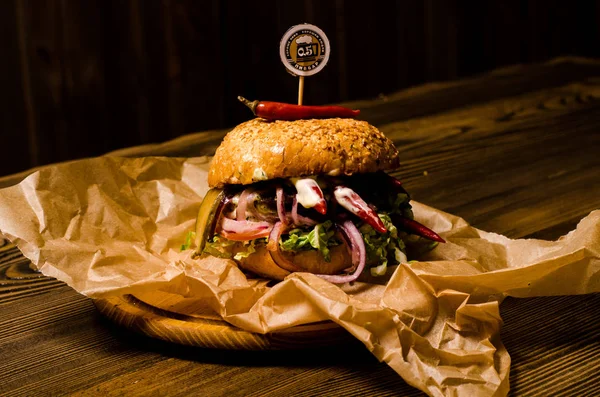 Slaninový burger s hovězí plackou na dřevěném stole — Stock fotografie